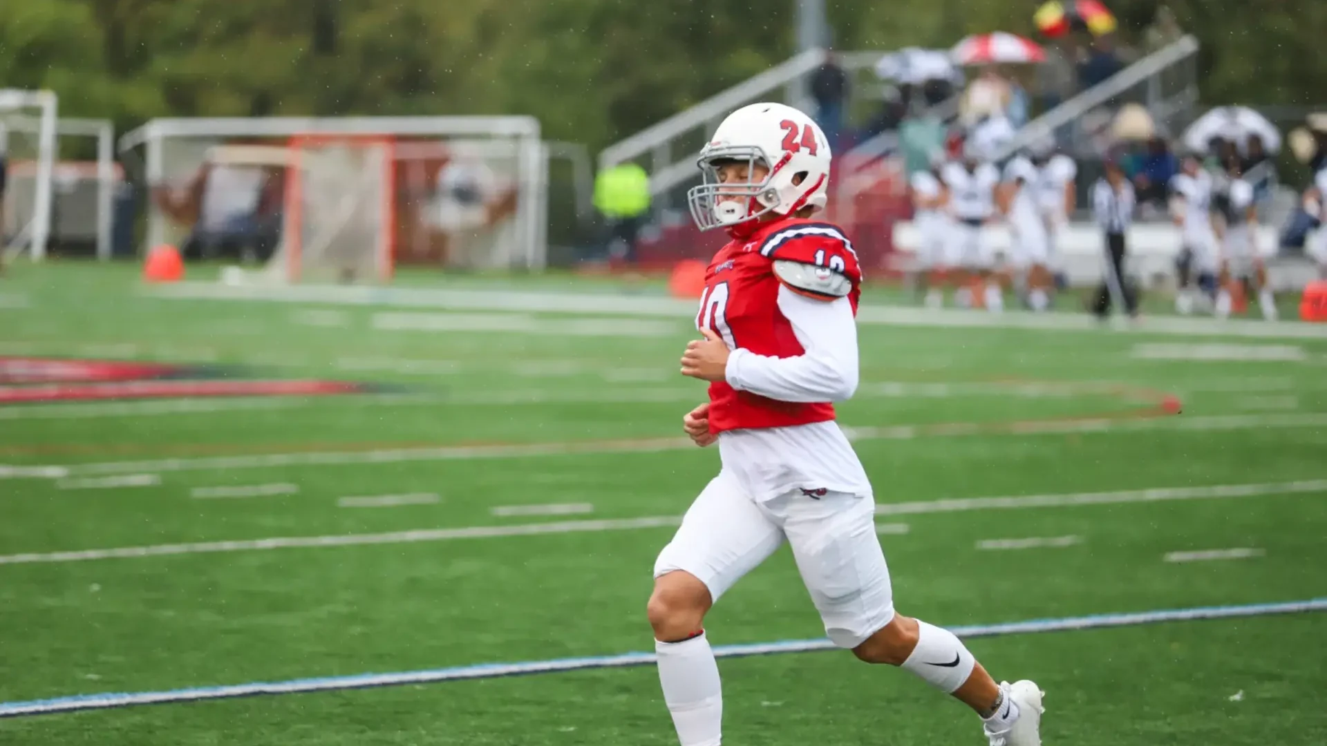 Female Football Player on an American football field wearing a red uniform and white helmet