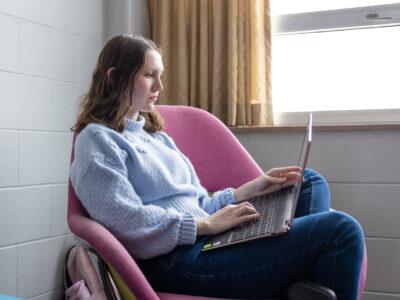 Female student studying in a residence hall common area on a college campus.